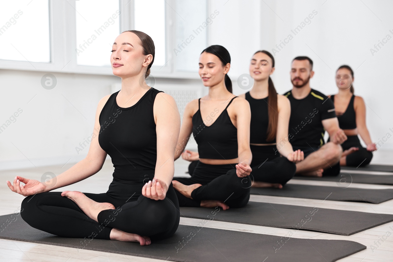 Photo of Group of people meditating on mats in yoga class