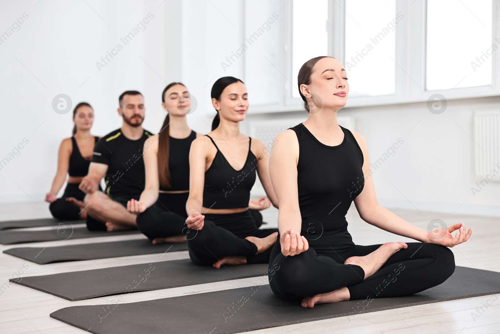 Photo of Group of people meditating on mats in yoga class