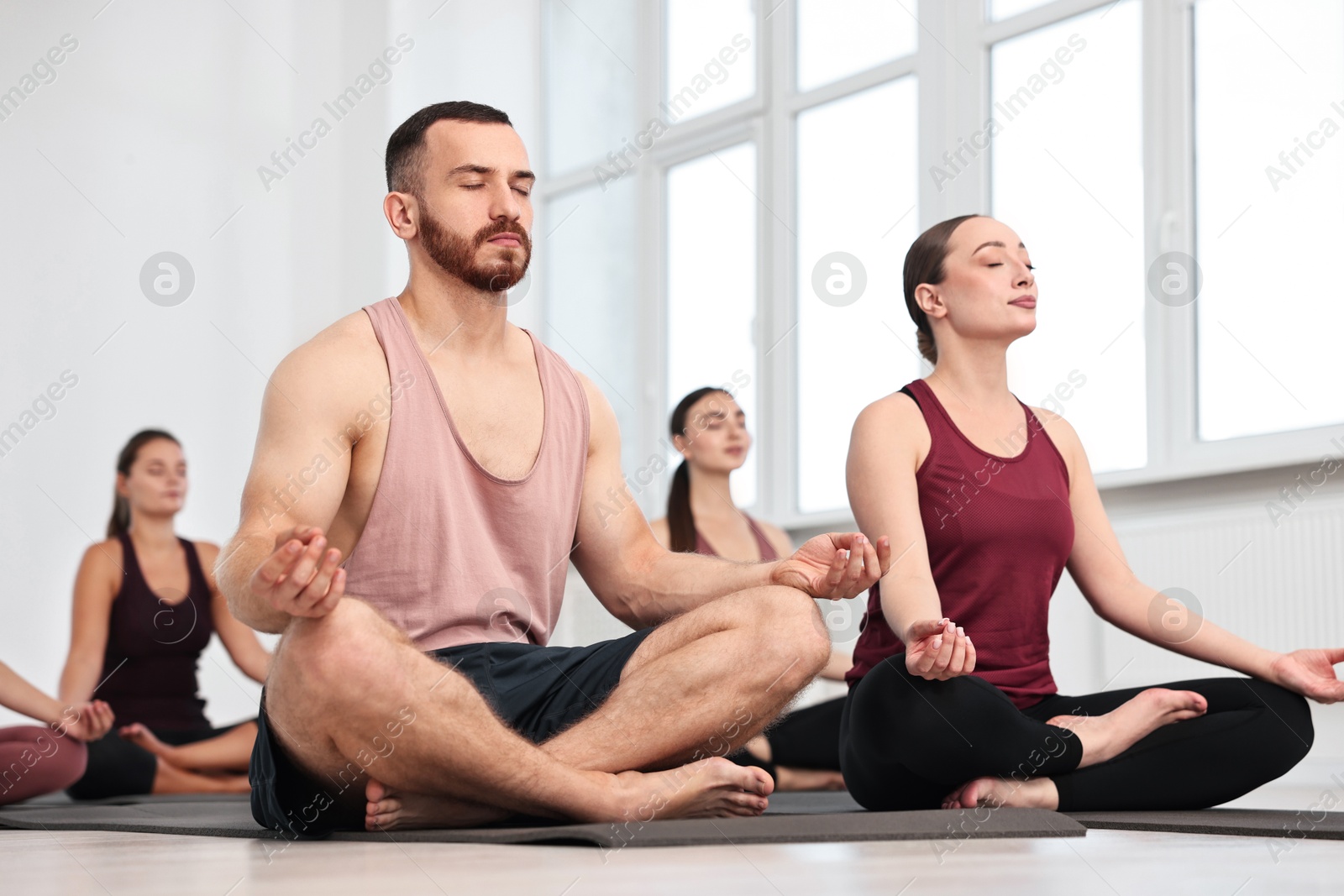 Photo of Group of people meditating on mats in yoga class