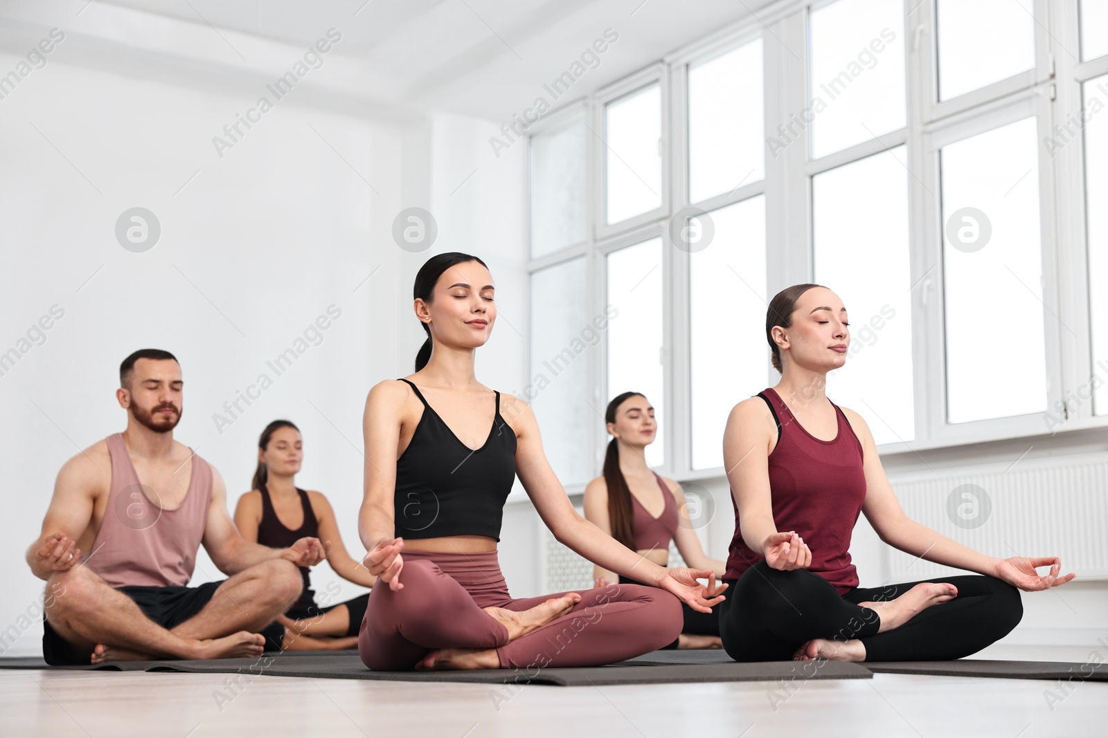 Photo of Group of people meditating on mats in yoga class