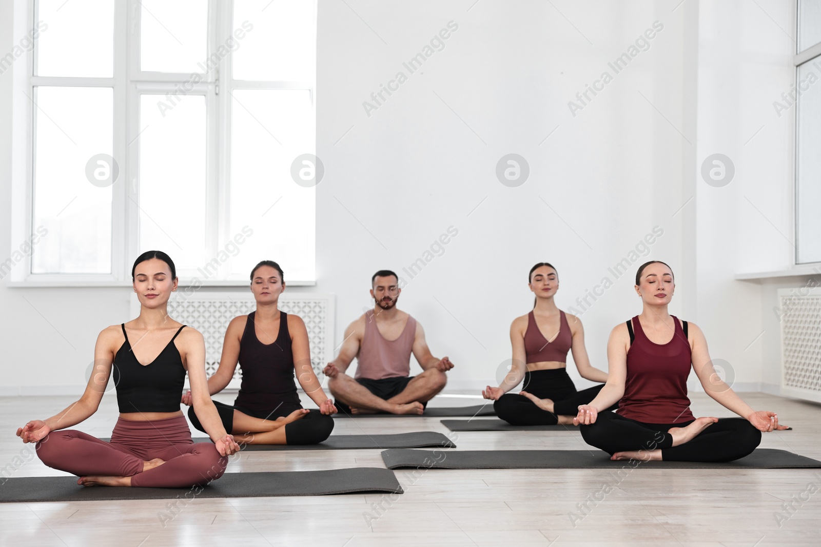 Photo of Group of people meditating on mats in yoga class