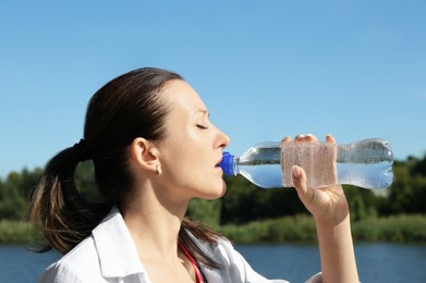 Photo of Woman drinking tasty soda water outdoors on sunny day