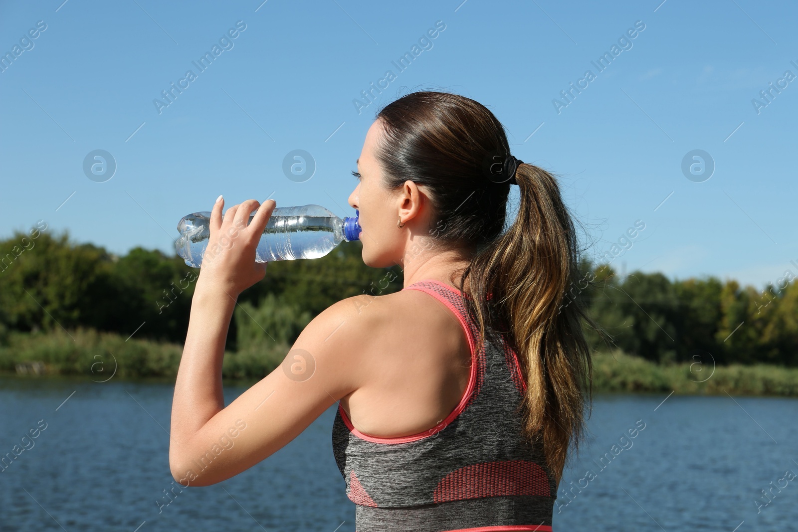 Photo of Woman drinking tasty soda water outdoors, back view