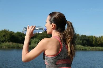 Photo of Woman drinking tasty soda water outdoors, back view