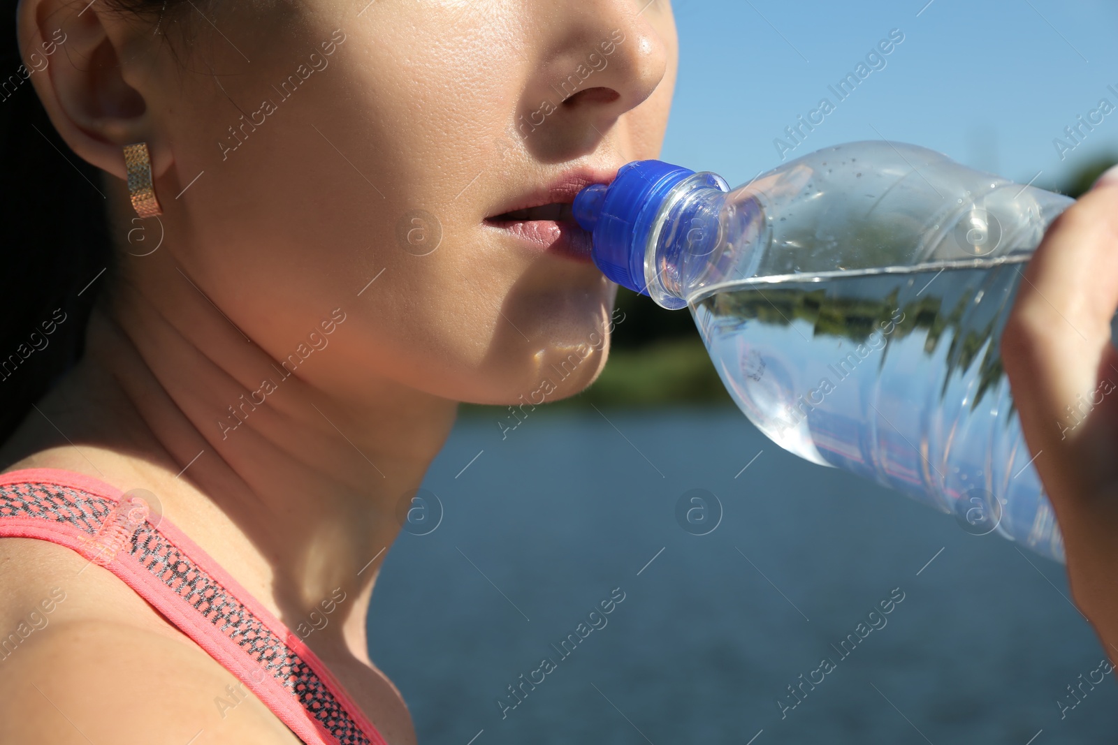 Photo of Woman drinking tasty soda water outdoors, closeup