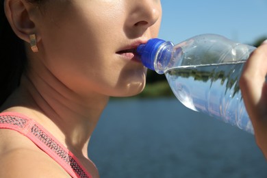 Photo of Woman drinking tasty soda water outdoors, closeup