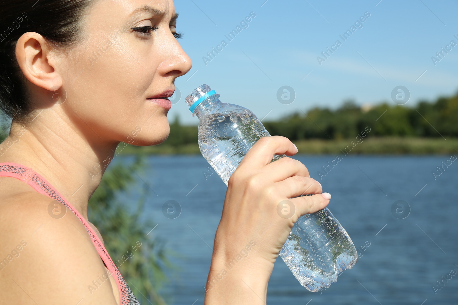 Photo of Woman drinking tasty soda water outdoors, closeup