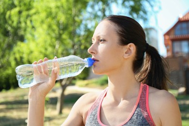 Photo of Woman drinking tasty soda water outdoors on sunny day