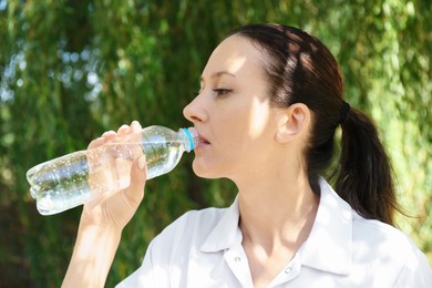 Photo of Woman drinking tasty soda water outdoors on sunny day