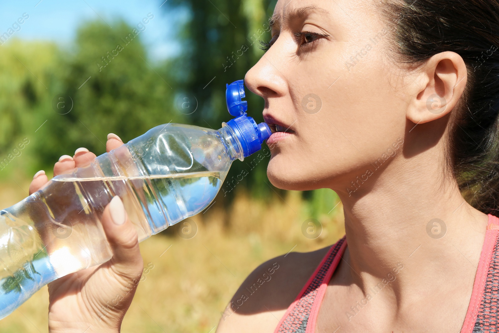 Photo of Woman drinking tasty soda water outdoors, closeup