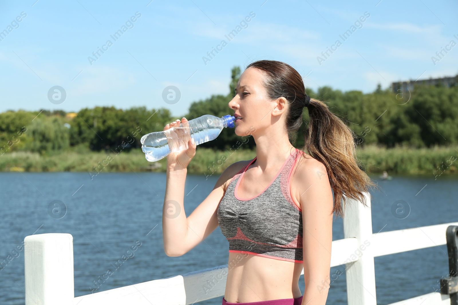 Photo of Woman drinking tasty soda water outdoors on sunny day