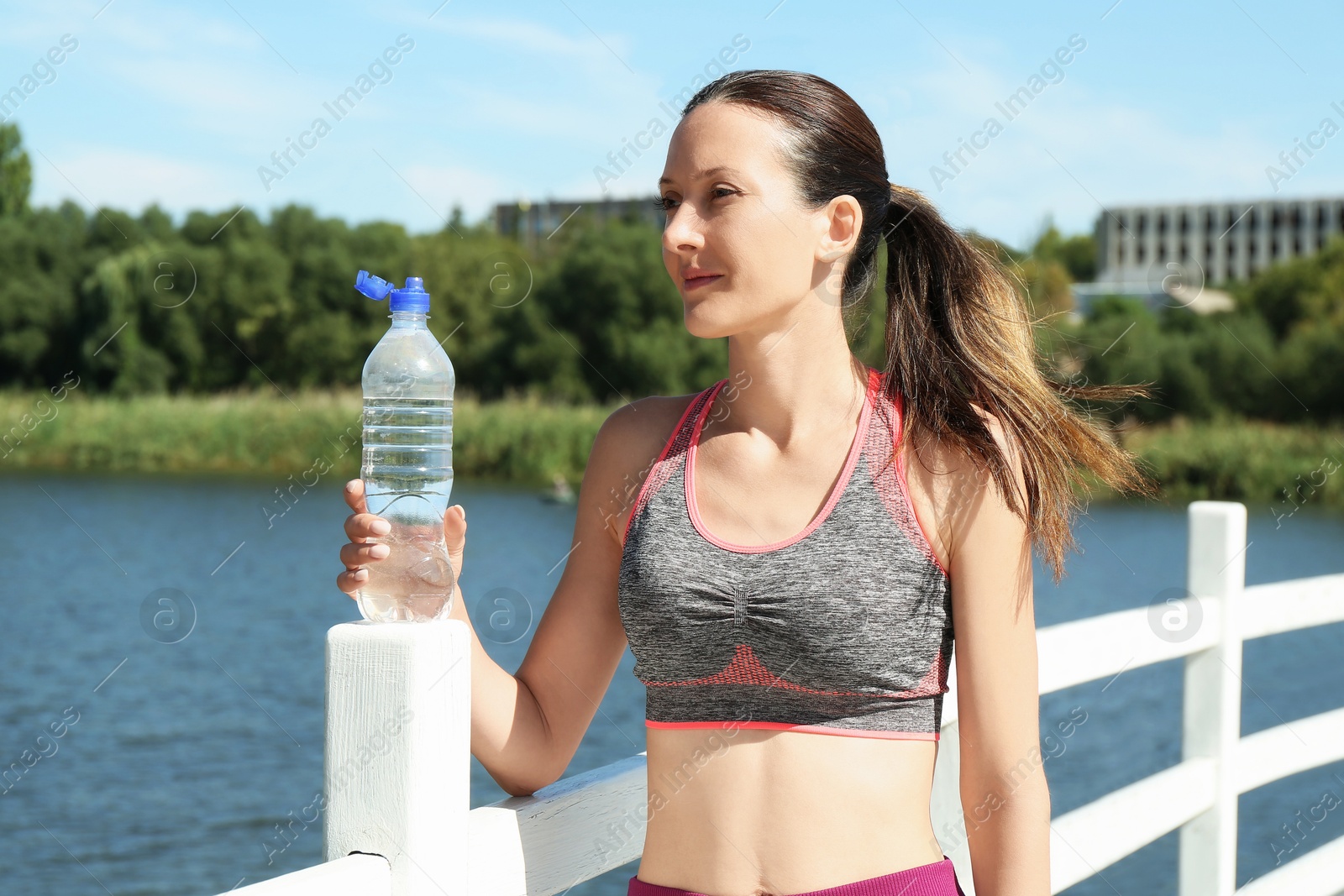 Photo of Woman with bottle of soda water outdoors on sunny day