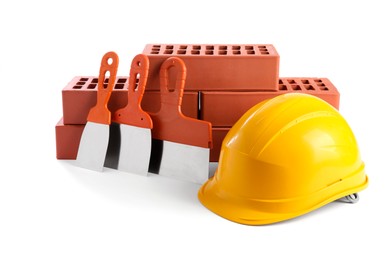 Yellow hard hat, red bricks and putty knives isolated on white. Building material and construction tools