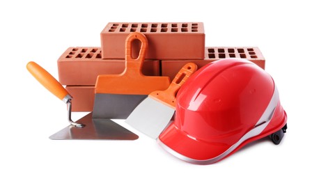 Photo of Orange hard hat, red bricks, trowel and putty knives isolated on white. Building material and construction tools