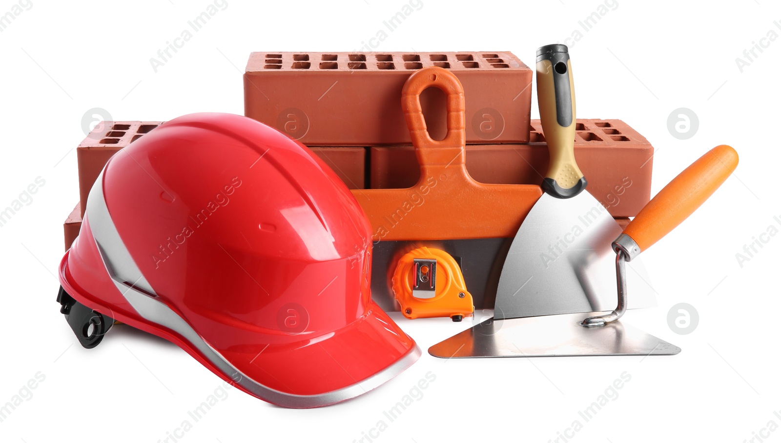 Photo of Orange hard hat, red bricks, trowel, measuring tape and putty knives isolated on white. Building material and construction tools