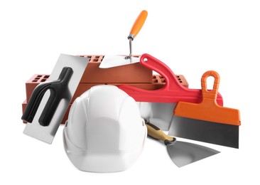 Photo of Hard hat, red bricks, trowel and putty knives isolated on white. Building material and construction tools