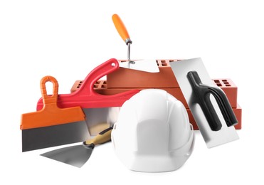 Hard hat, red bricks, trowel and putty knives isolated on white. Building material and construction tools