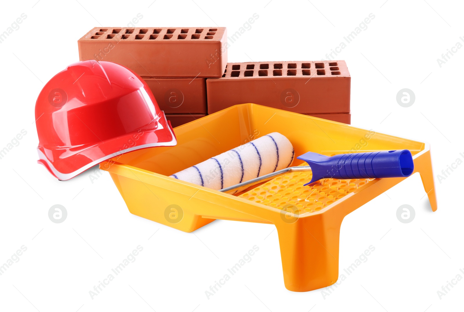 Photo of Orange hard hat, red bricks, roller and tray isolated on white. Building material and construction tools