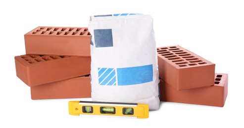 Cement powder in bag, red bricks and building level isolated on white