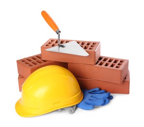 Photo of Red bricks, trowel, yellow hard hat and gloves isolated on white. Building material and construction tools