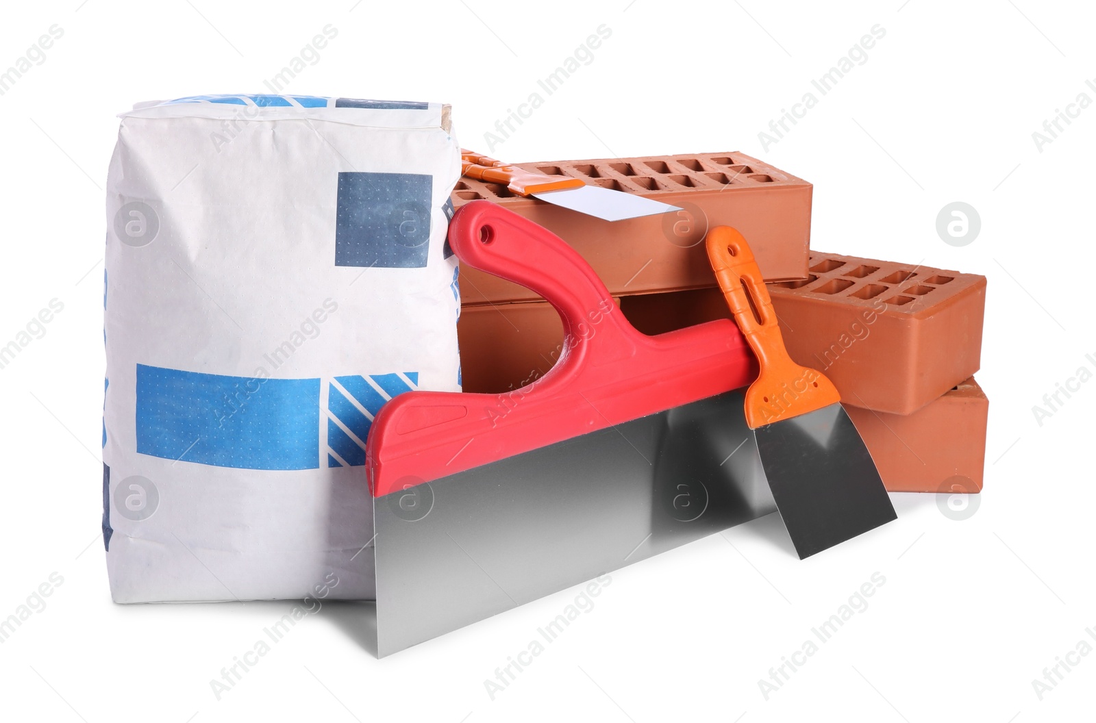 Photo of Cement powder in bag, red bricks and putty knives isolated on white. Building materials and construction tools