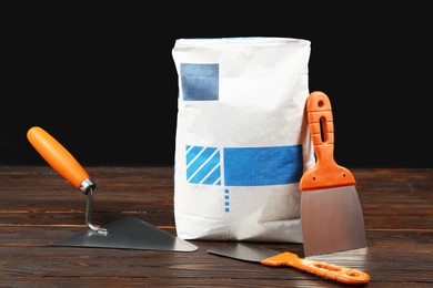 Bag of cement powder and putty knives on wooden table. Building material