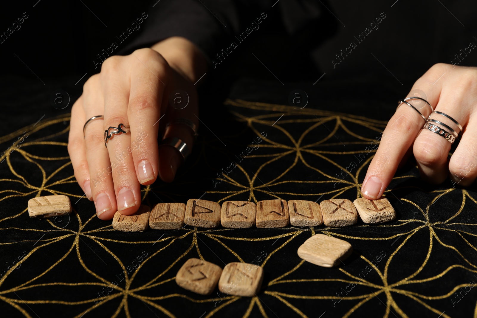 Photo of Woman with wooden runes at divination mat, closeup