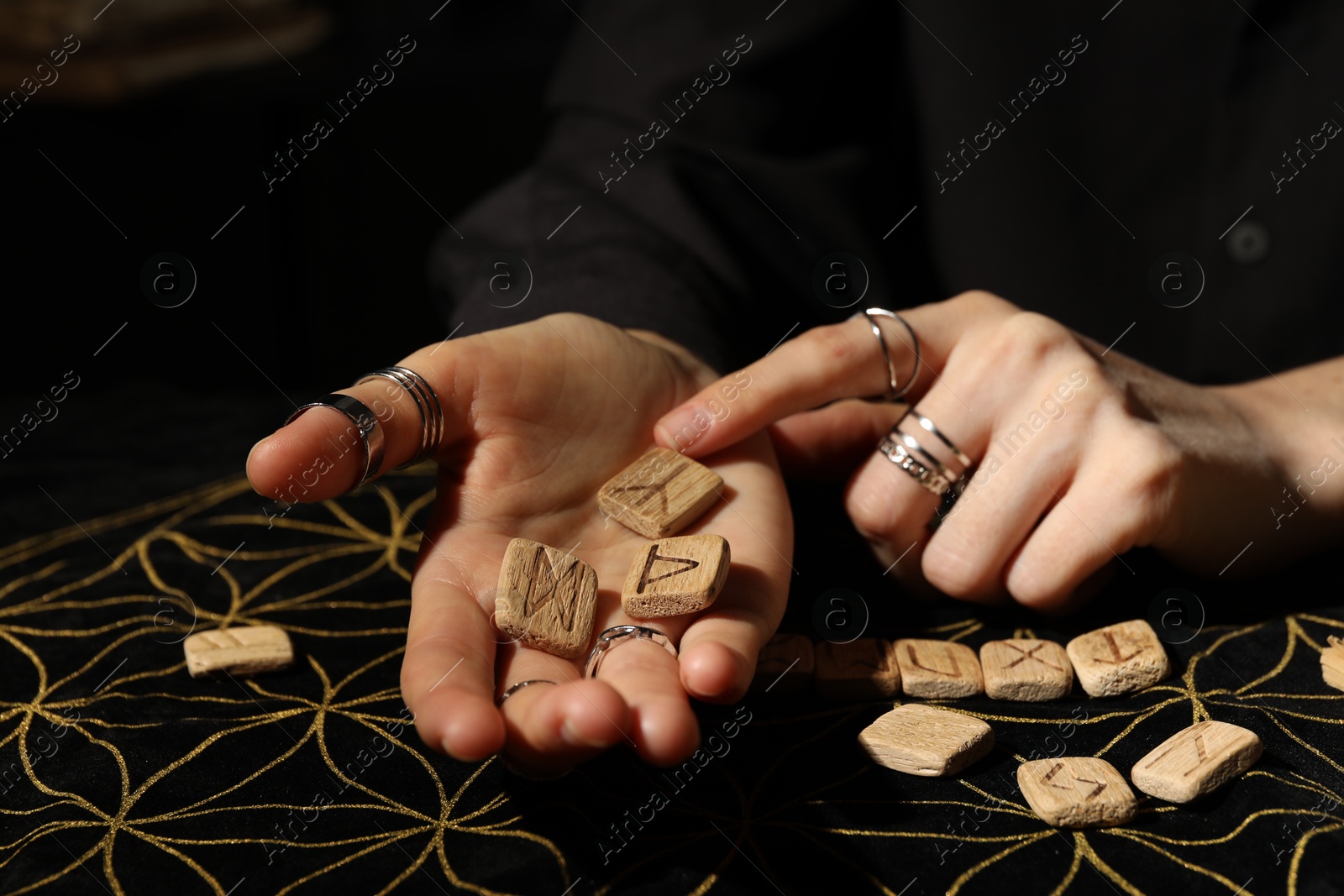 Photo of Woman with wooden runes at divination mat, closeup