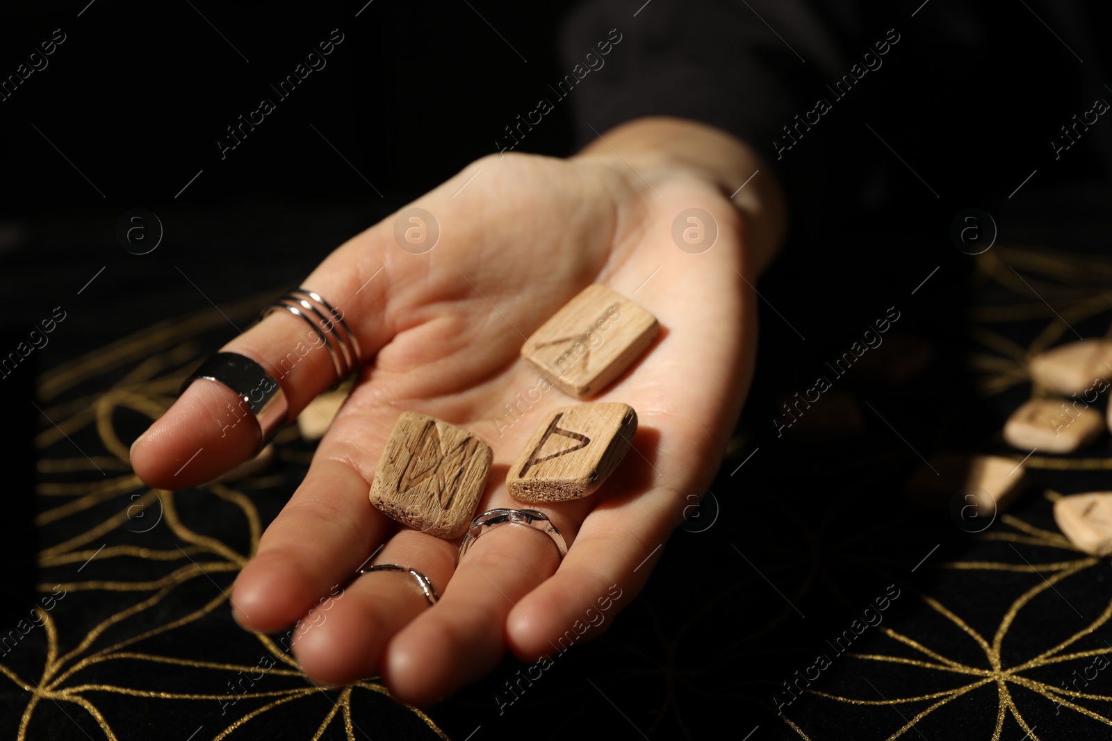 Photo of Woman with wooden runes at divination mat, closeup