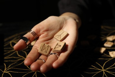 Photo of Woman with wooden runes at divination mat, closeup