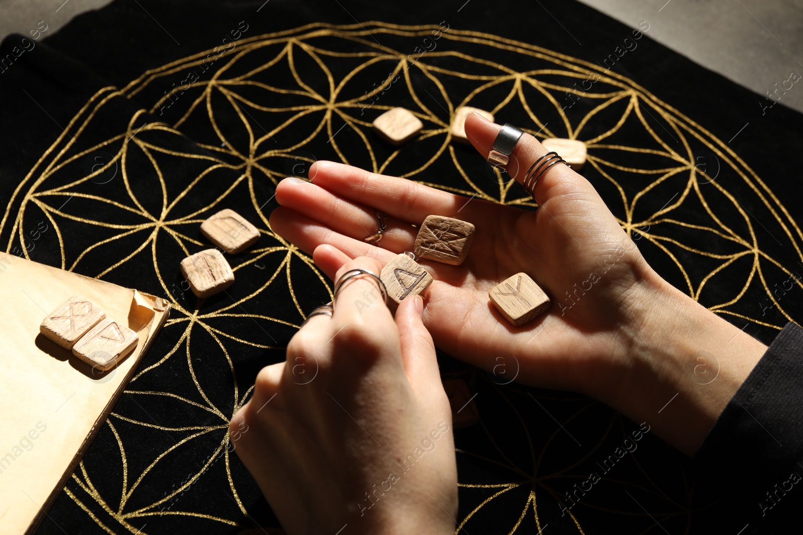 Photo of Woman with wooden runes at divination mat, closeup