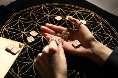 Photo of Woman with wooden runes at divination mat, closeup