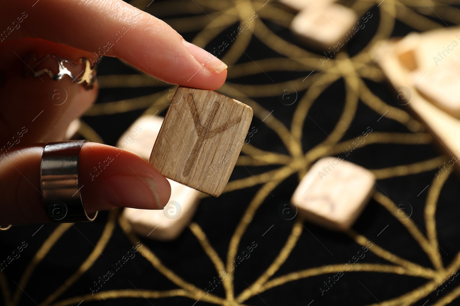 Photo of Woman with rune Algiz at divination mat, closeup