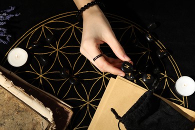 Photo of Woman with black runes at divination mat, top view