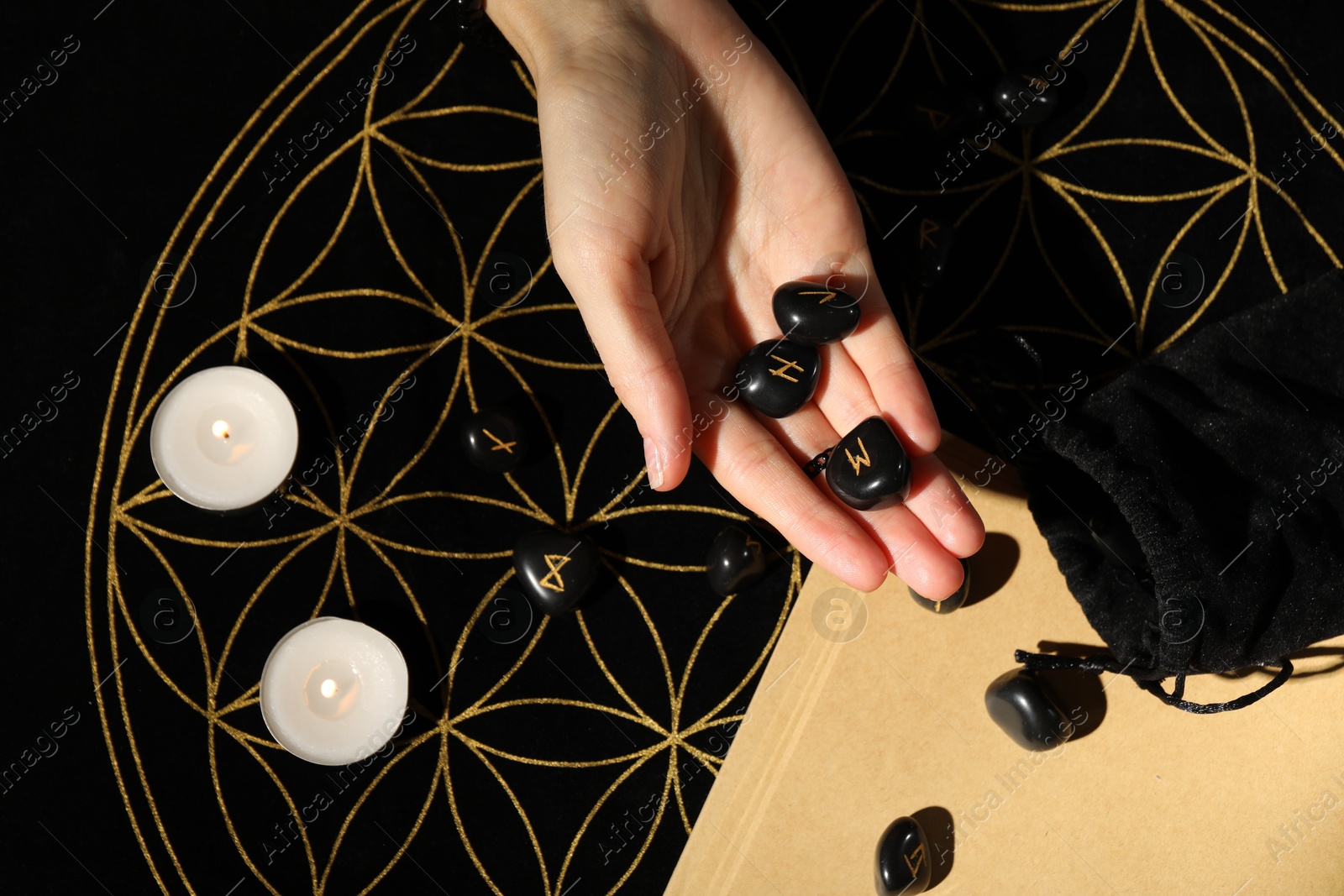 Photo of Woman with black runes at divination mat, top view