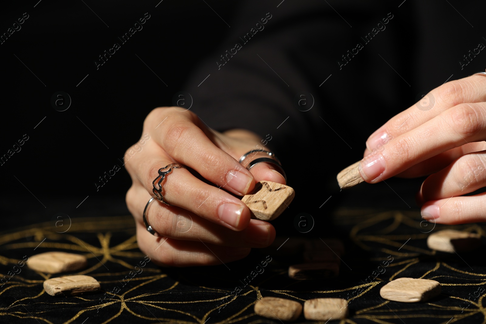 Photo of Woman with wooden runes at divination mat, closeup