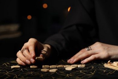 Photo of Woman with wooden runes at divination mat, closeup