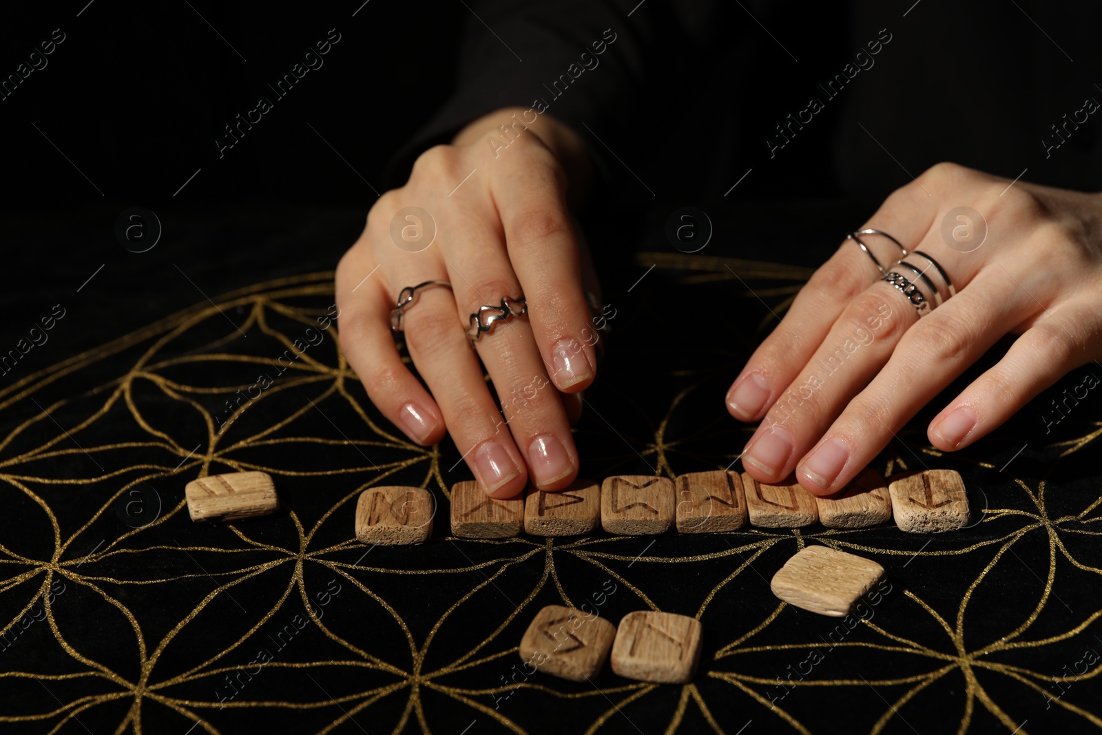 Photo of Woman with wooden runes at divination mat, closeup