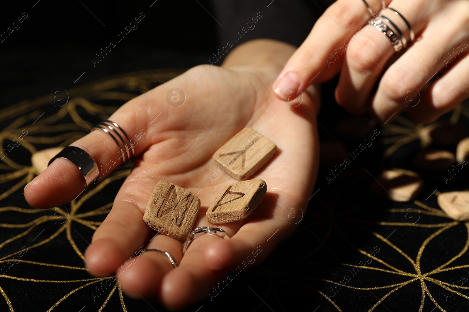 Photo of Woman with wooden runes at divination mat, closeup