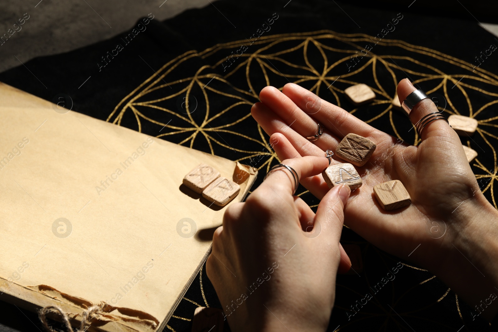 Photo of Woman with wooden runes at divination mat, closeup