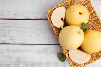 Photo of Delicious fresh apple pears in basket on white wooden table, top view. Space for text