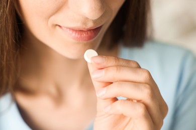 Photo of Woman taking pill on blurred background, closeup