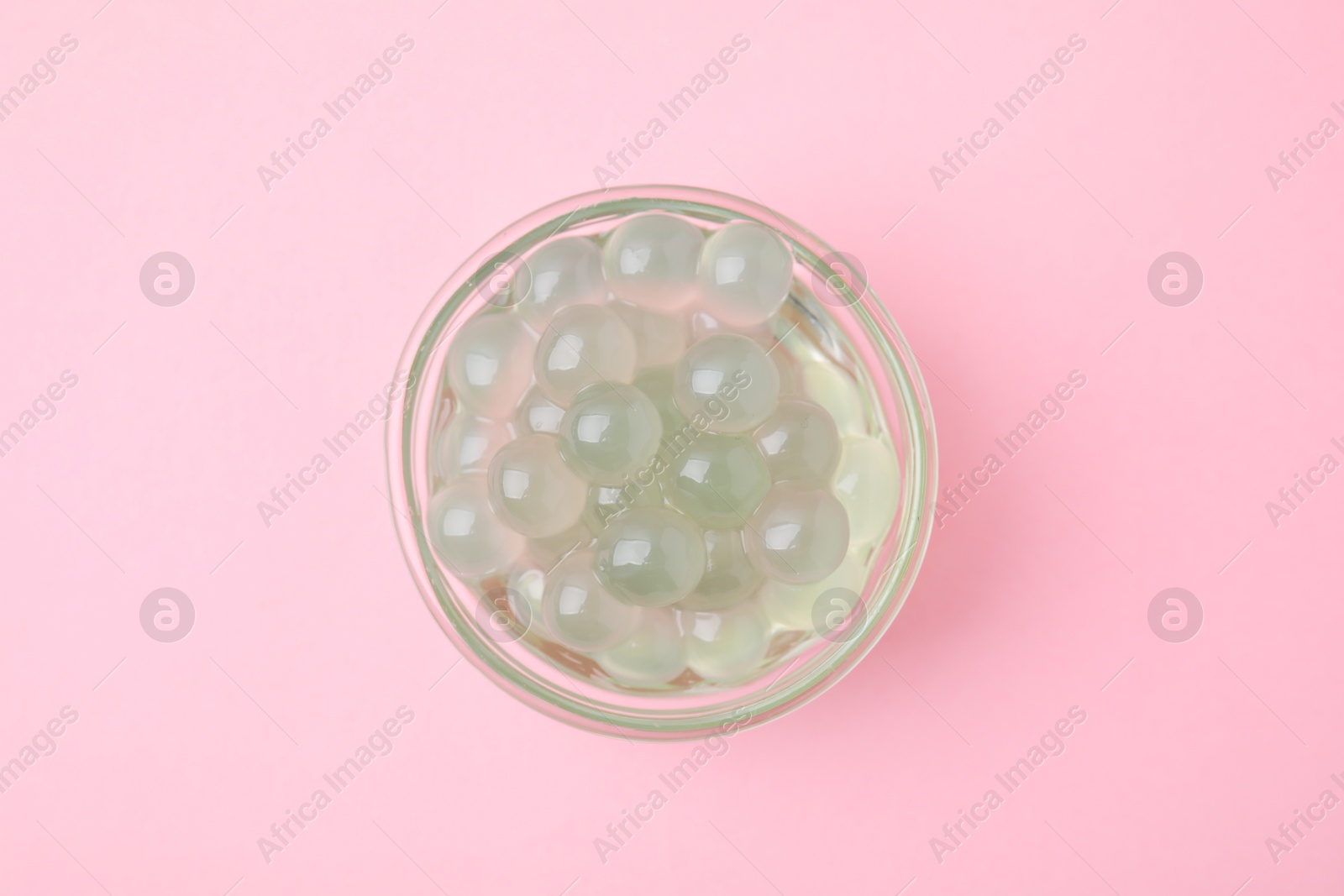 Photo of Tapioca pearls in bowl on pink background, top view