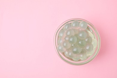 Photo of Tapioca pearls in bowl on pink background, top view. Space for text