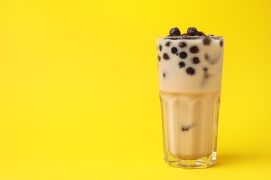 Photo of Tasty milk bubble tea in glass on yellow background, space for text