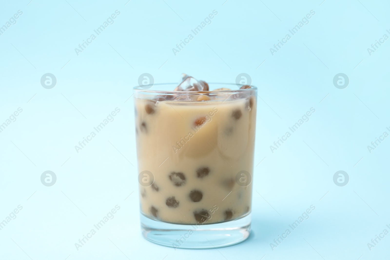 Photo of Tasty milk bubble tea in glass on light blue background