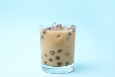 Photo of Tasty milk bubble tea in glass on light blue background