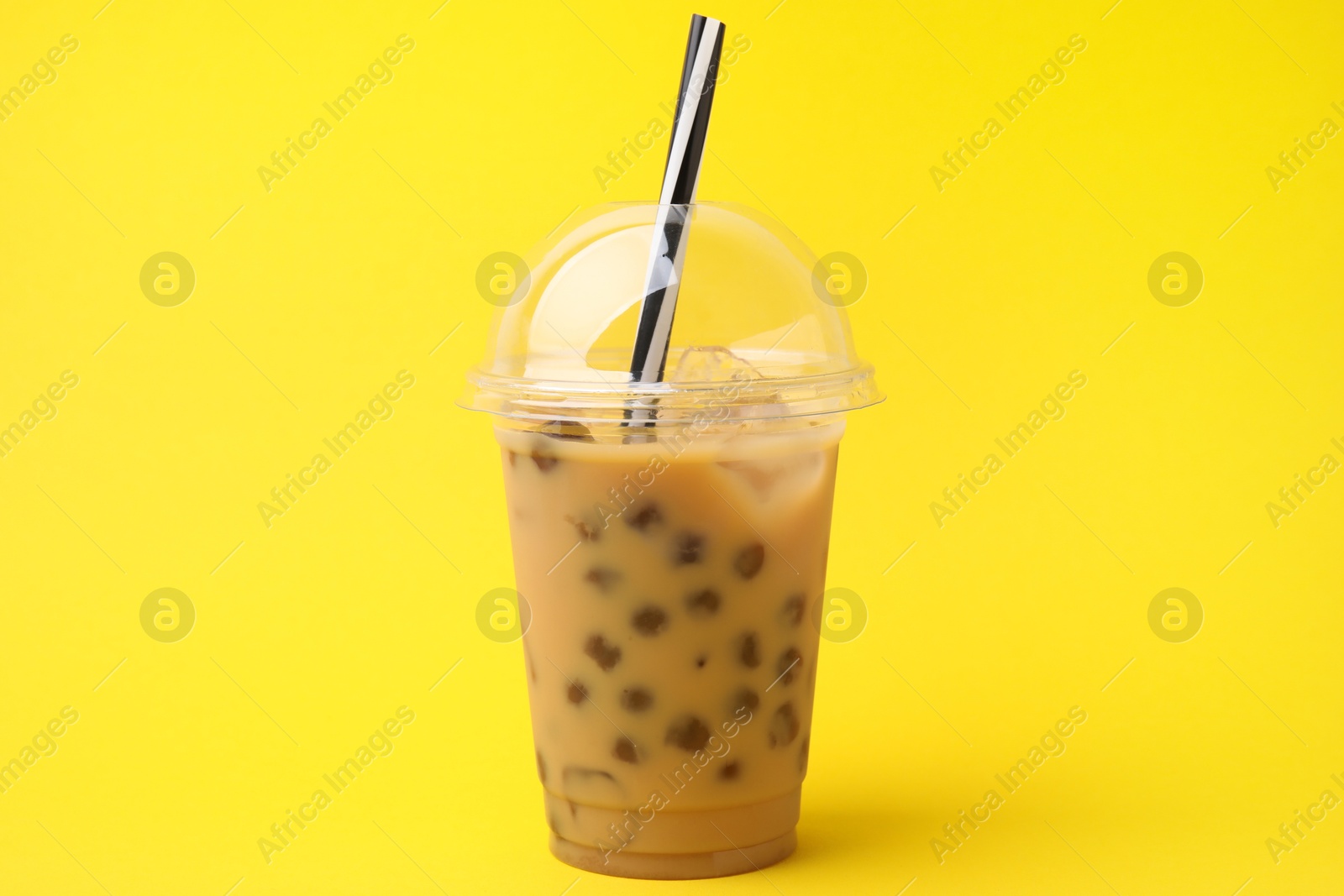 Photo of Tasty milk bubble tea in plastic cups on yellow background