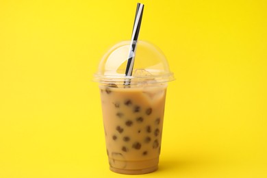 Tasty milk bubble tea in plastic cups on yellow background