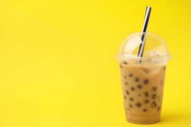 Photo of Tasty milk bubble tea in plastic cups on yellow background, space for text